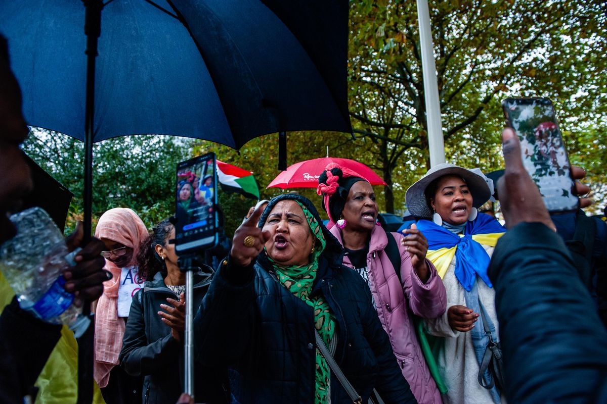 A Sudanese woman, flanked by other woman, shakes her finger at a mobile phone camera. 